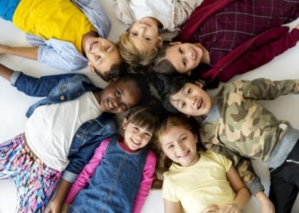 Group primary schoolers lying ground smiling 1024x796