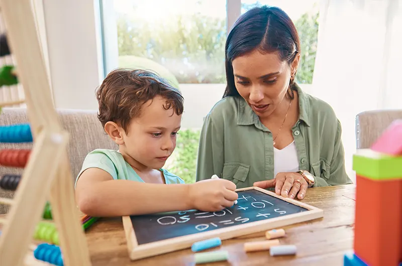 Child mother chalkboard writing math numbers home school development happy family help support biracial woman mom kindergarten kid with learning teaching education
